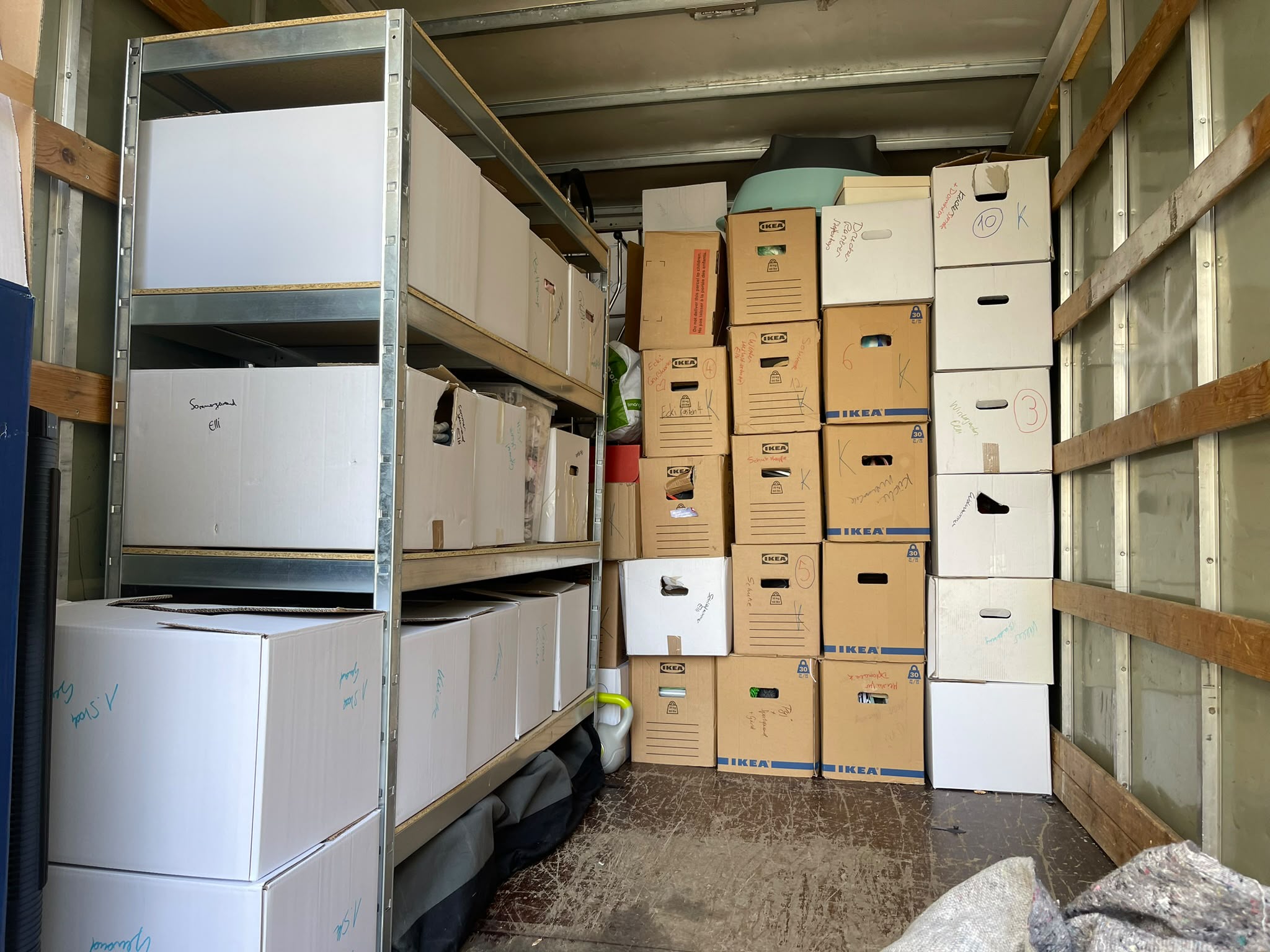 Beschriftete Umzugskartons und Regal im LKW