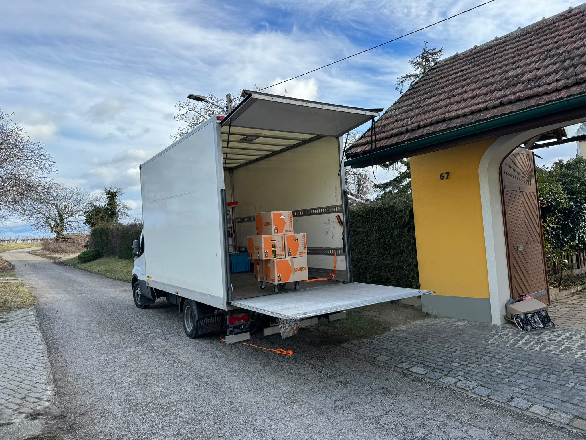 Umzugs-LKW mit offener Ladebordwand vor einem Haus